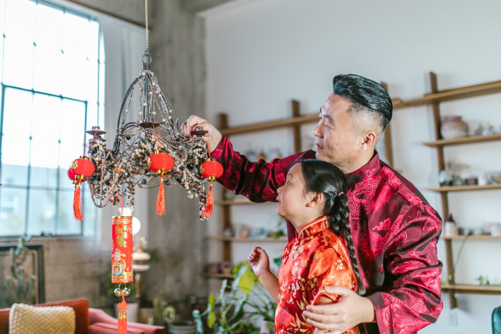 Father and daughter placing décor on chandelier for Lunar New Year
