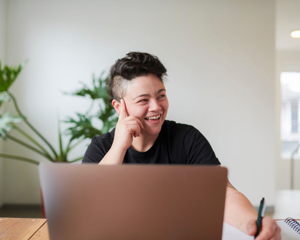 Trans man smiling and sitting in front of laptop