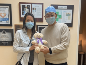 Happy Asian woman and Asian male doctor holding teddy bear together