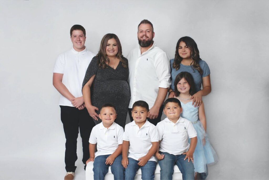 family photo of couple pregnant through IVF and their 6 adopted children