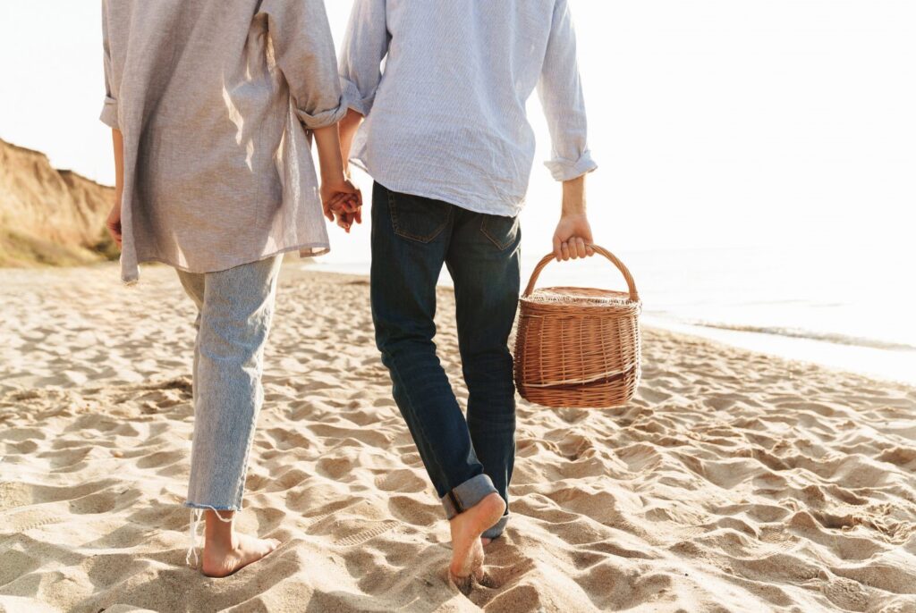 couple keeping the romance alive by holding hands at beach for a picnic date