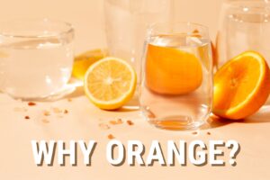 Orange color themed image with glasses of water and cuts of oranges White text in the center reads "Why Orange?"